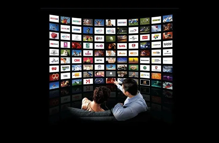 Kijker voor een muur vol tv-zenders